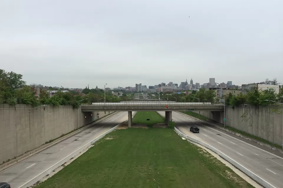 View from overpass of highway with one truck and green median with Baltimore city in the background